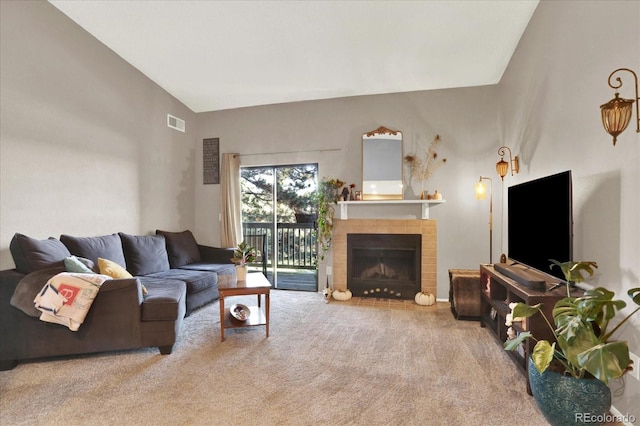 carpeted living room featuring a tiled fireplace and high vaulted ceiling