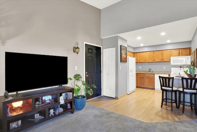 interior space with light wood-type flooring, white appliances, sink, and a high ceiling