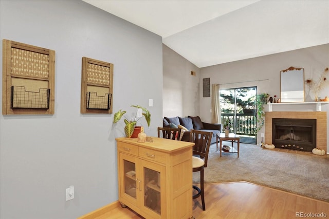 interior space featuring vaulted ceiling, a tiled fireplace, and light hardwood / wood-style floors