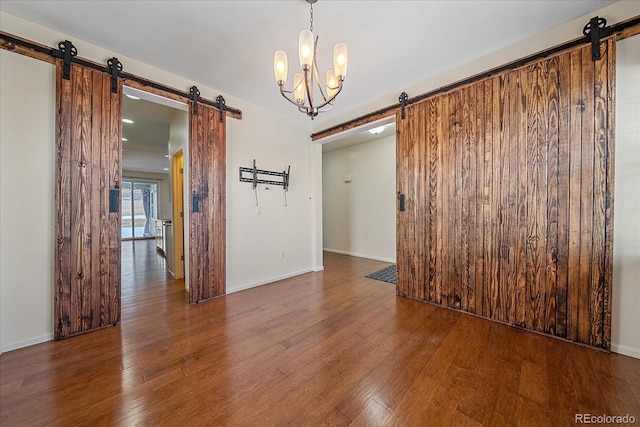 unfurnished room featuring a barn door and dark hardwood / wood-style flooring