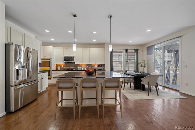 kitchen featuring white cabinetry, a kitchen breakfast bar, hanging light fixtures, a center island, and stainless steel appliances