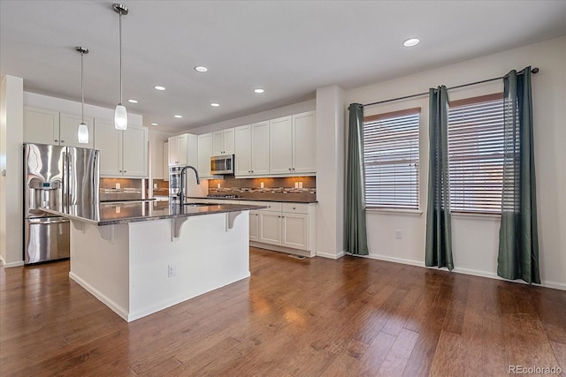 kitchen featuring appliances with stainless steel finishes, decorative light fixtures, sink, a kitchen breakfast bar, and a center island with sink