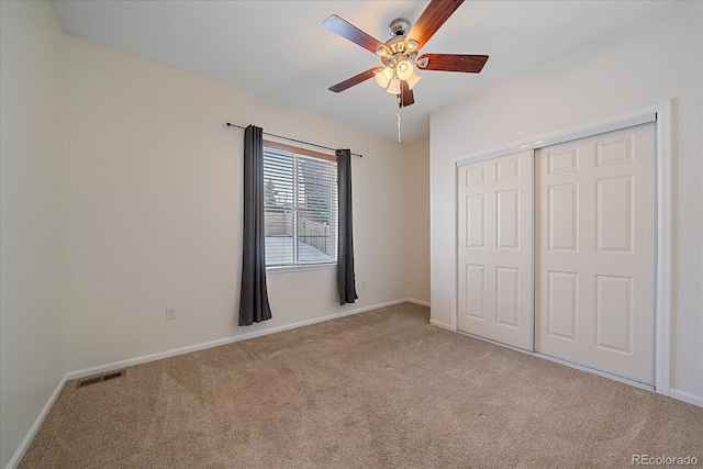 unfurnished bedroom featuring light colored carpet, ceiling fan, and a closet