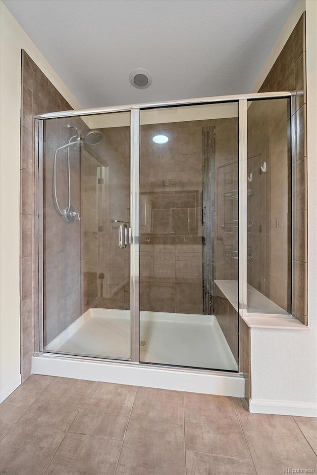 bathroom with an enclosed shower and tile patterned flooring