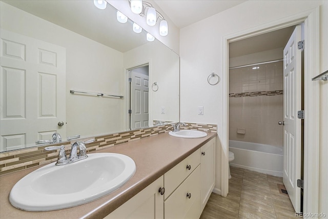 full bathroom with vanity, toilet, tiled shower / bath combo, and backsplash