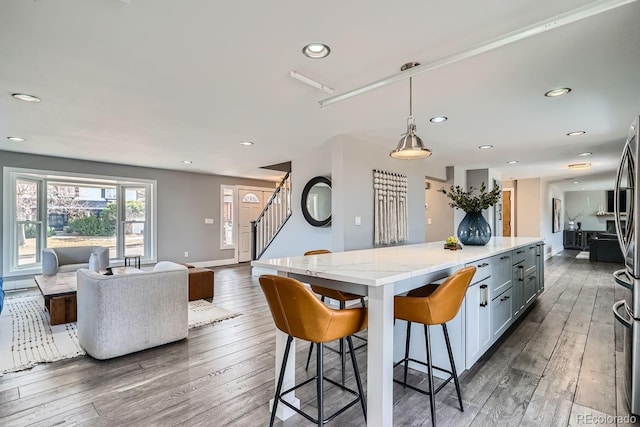 kitchen featuring a kitchen island, open floor plan, dark wood-type flooring, a kitchen breakfast bar, and hanging light fixtures