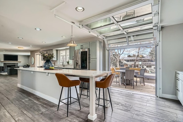 kitchen featuring decorative light fixtures, light countertops, dark wood-type flooring, a kitchen breakfast bar, and stainless steel fridge with ice dispenser