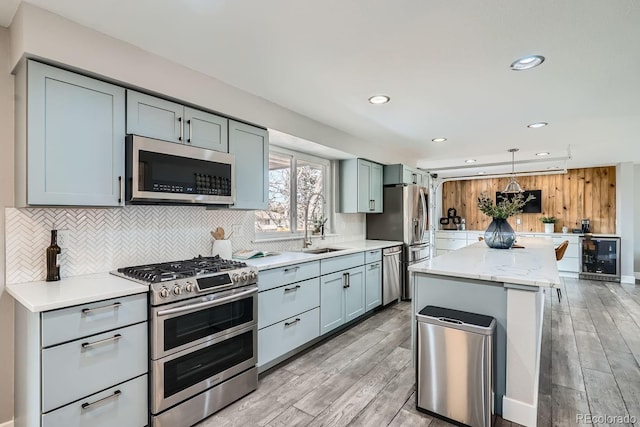 kitchen featuring light stone counters, wine cooler, stainless steel appliances, hanging light fixtures, and backsplash