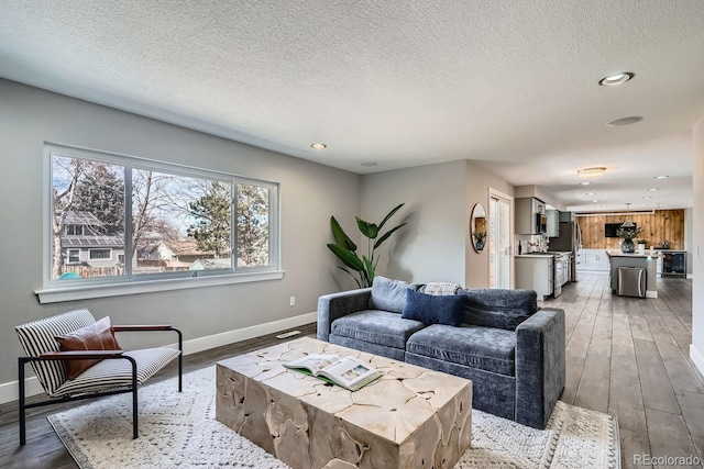 living room featuring wood-type flooring, a textured ceiling, and baseboards