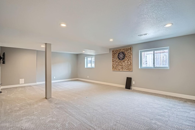 basement featuring recessed lighting, light colored carpet, visible vents, a textured ceiling, and baseboards