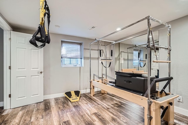 workout area with baseboards, visible vents, and wood finished floors