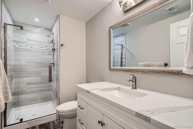 bathroom featuring visible vents, toilet, a textured ceiling, vanity, and a shower stall