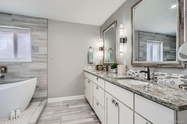 full bathroom featuring baseboards, a sink, a freestanding bath, and double vanity