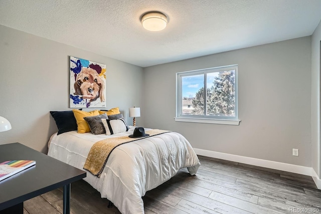 bedroom with a textured ceiling, wood finished floors, and baseboards