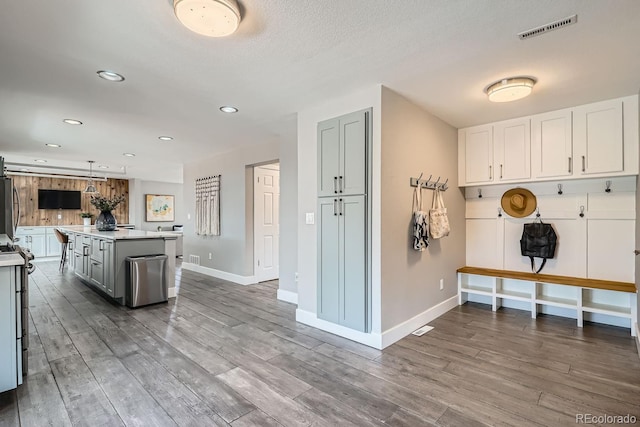 kitchen featuring gray cabinetry, wood finished floors, a kitchen island, visible vents, and light countertops