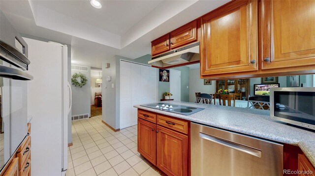 663 S Xenon Ct, Lakewood, CO 80228 - kitchen with stainless steel appliances, light tile patterned floors, under cabinet range hood, a tray ceiling, and light countertops