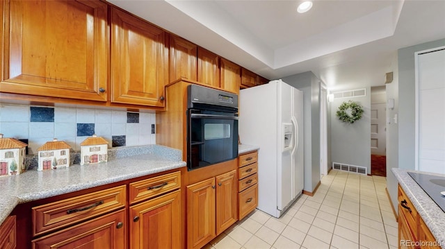 663 S Xenon Ct, Lakewood, CO 80228 - kitchen with black appliances, light tile patterned floors, brown cabinets, a tray ceiling, and backsplash