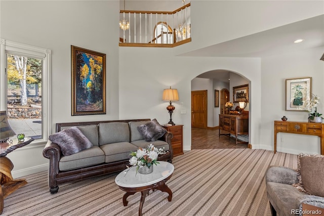 carpeted living area with arched walkways, a high ceiling, baseboards, and recessed lighting