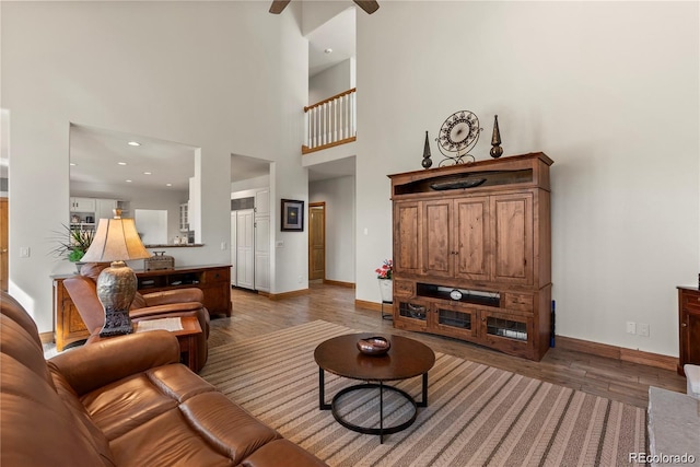 living area featuring a high ceiling, wood finished floors, and baseboards