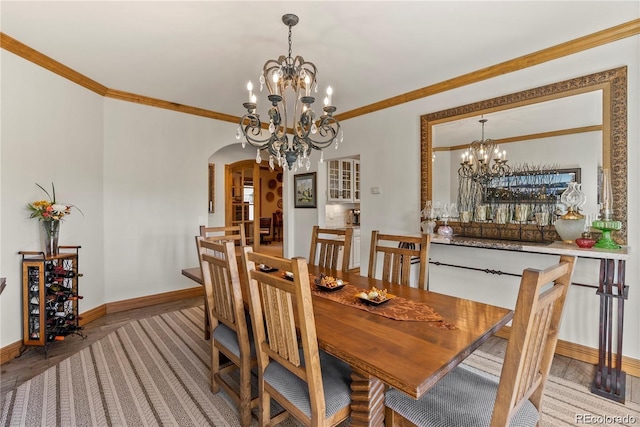 dining room with baseboards, crown molding, arched walkways, and an inviting chandelier