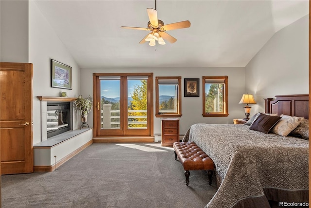 bedroom with carpet, lofted ceiling, a baseboard heating unit, a glass covered fireplace, and baseboards