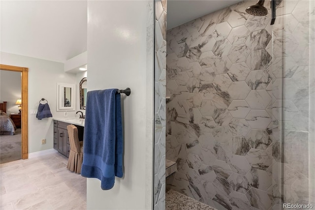 full bathroom with ensuite bathroom, a tile shower, vanity, and baseboards