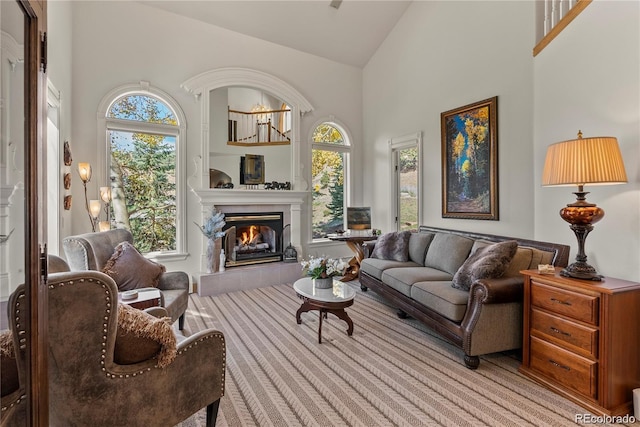 sitting room with high vaulted ceiling, a tiled fireplace, and a healthy amount of sunlight