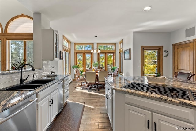 kitchen featuring visible vents, dishwasher, backsplash, wood finished floors, and a sink