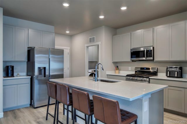 kitchen with visible vents, a sink, a kitchen breakfast bar, stainless steel appliances, and light wood-style floors