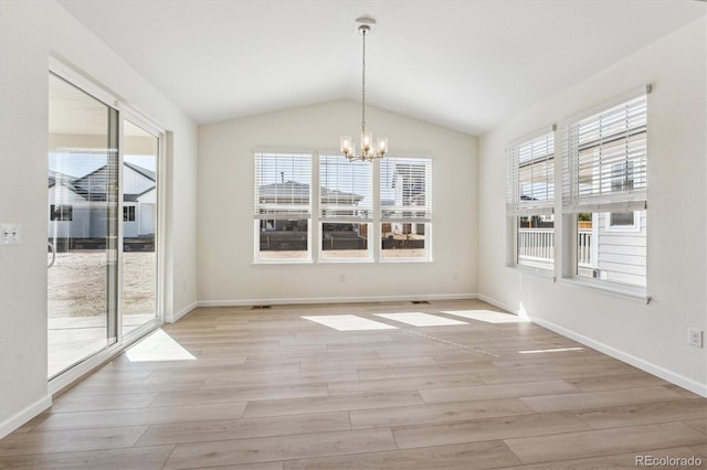 unfurnished dining area featuring an inviting chandelier, a wealth of natural light, lofted ceiling, and light wood-type flooring