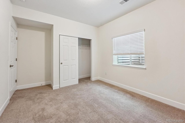 unfurnished bedroom with light carpet and a closet