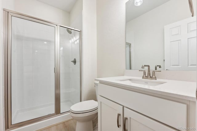 bathroom featuring vanity, hardwood / wood-style floors, a shower with shower door, and toilet