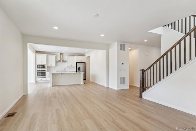 unfurnished living room featuring sink and light hardwood / wood-style flooring