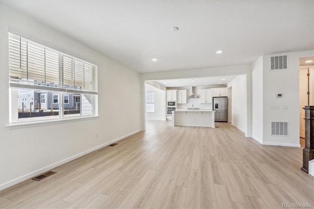 unfurnished living room featuring sink and light hardwood / wood-style floors