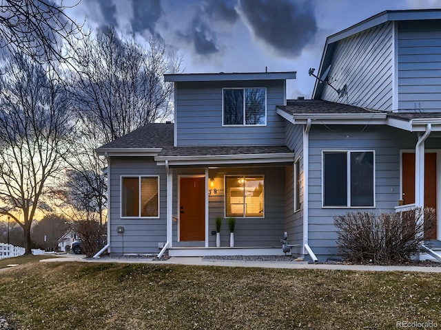 view of front of home featuring a shingled roof and a lawn