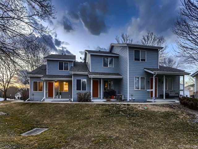 rear view of house featuring covered porch and a lawn