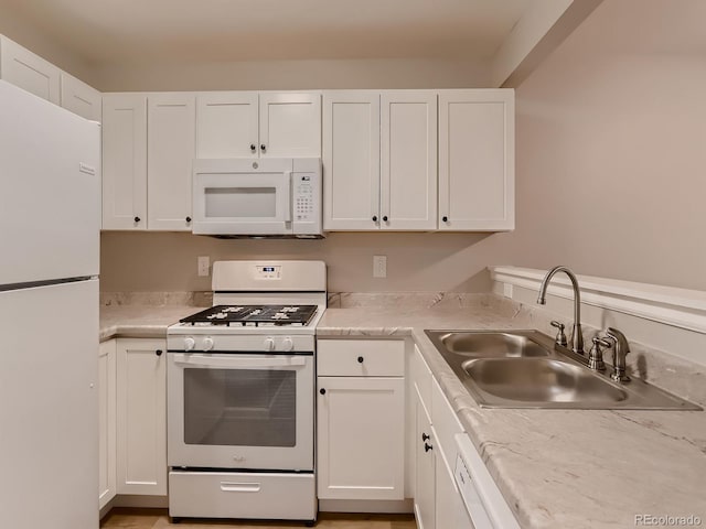 kitchen featuring white appliances, white cabinets, and a sink