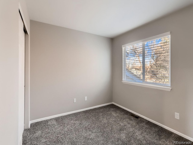 unfurnished bedroom featuring dark colored carpet, a closet, visible vents, and baseboards