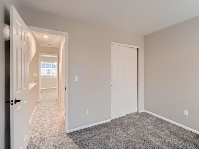 unfurnished bedroom with a closet, carpet flooring, and baseboards