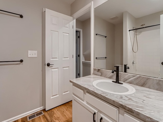 full bathroom featuring a shower, visible vents, vanity, wood finished floors, and baseboards