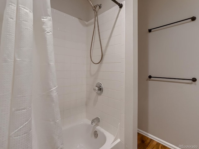 full bath with baseboards, shower / bath combo with shower curtain, and wood finished floors