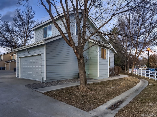 view of side of property with a garage, fence, and concrete driveway