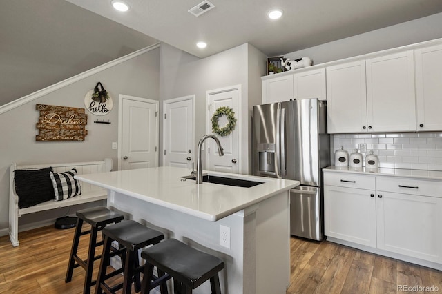 8765 Laurel Mountain Vw, Colorado Springs, CO 80924 - kitchen featuring stainless steel refrigerator with ice dispenser, a breakfast bar, white cabinetry, an island with sink, and decorative backsplash