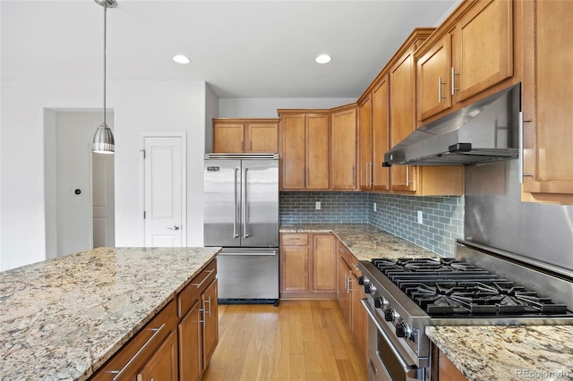 8987 E Otero Pl, Centennial, CO 80112 - kitchen with high end appliances, under cabinet range hood, brown cabinetry, light wood-type flooring, and recessed lighting