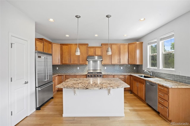 8987 E Otero Pl, Centennial, CO 80112 - kitchen featuring appliances with stainless steel finishes, under cabinet range hood, a kitchen island, backsplash, and light stone counters