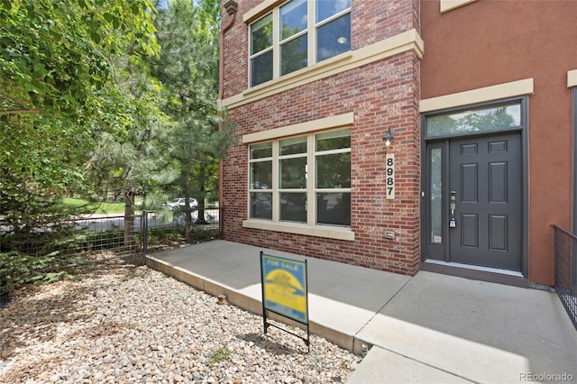 8987 E Otero Pl, Centennial, CO 80112 - doorway to property featuring brick siding and stucco siding