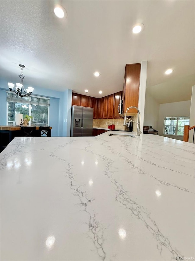16063 E 106th Ct, Commerce City, CO 80022 - kitchen with stainless steel appliances, recessed lighting, light stone countertops, a chandelier, and decorative backsplash