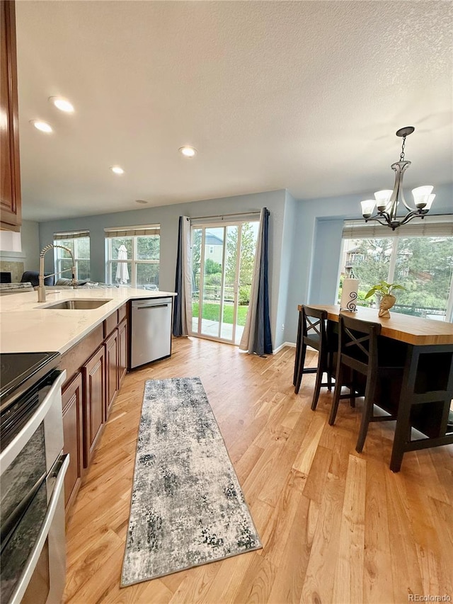 16063 E 106th Ct, Commerce City, CO 80022 - kitchen featuring stainless steel appliances, brown cabinetry, a chandelier, recessed lighting, and light wood finished floors
