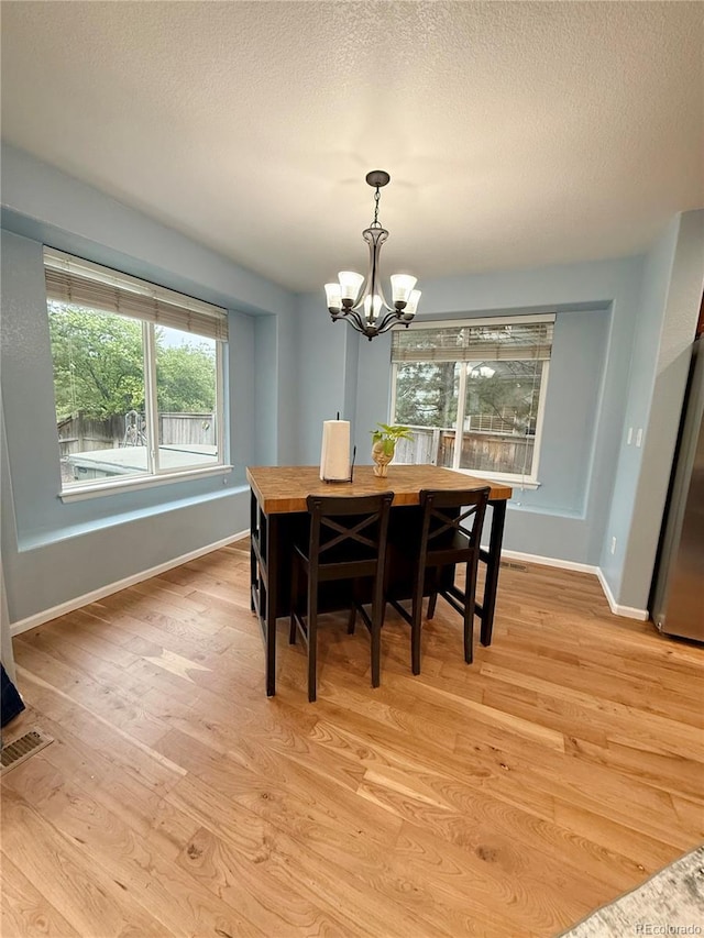 16063 E 106th Ct, Commerce City, CO 80022 - dining area featuring a chandelier, light wood finished floors, baseboards, and a textured ceiling