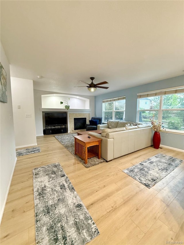 16063 E 106th Ct, Commerce City, CO 80022 - living room featuring light wood-type flooring, a glass covered fireplace, ceiling fan, and baseboards